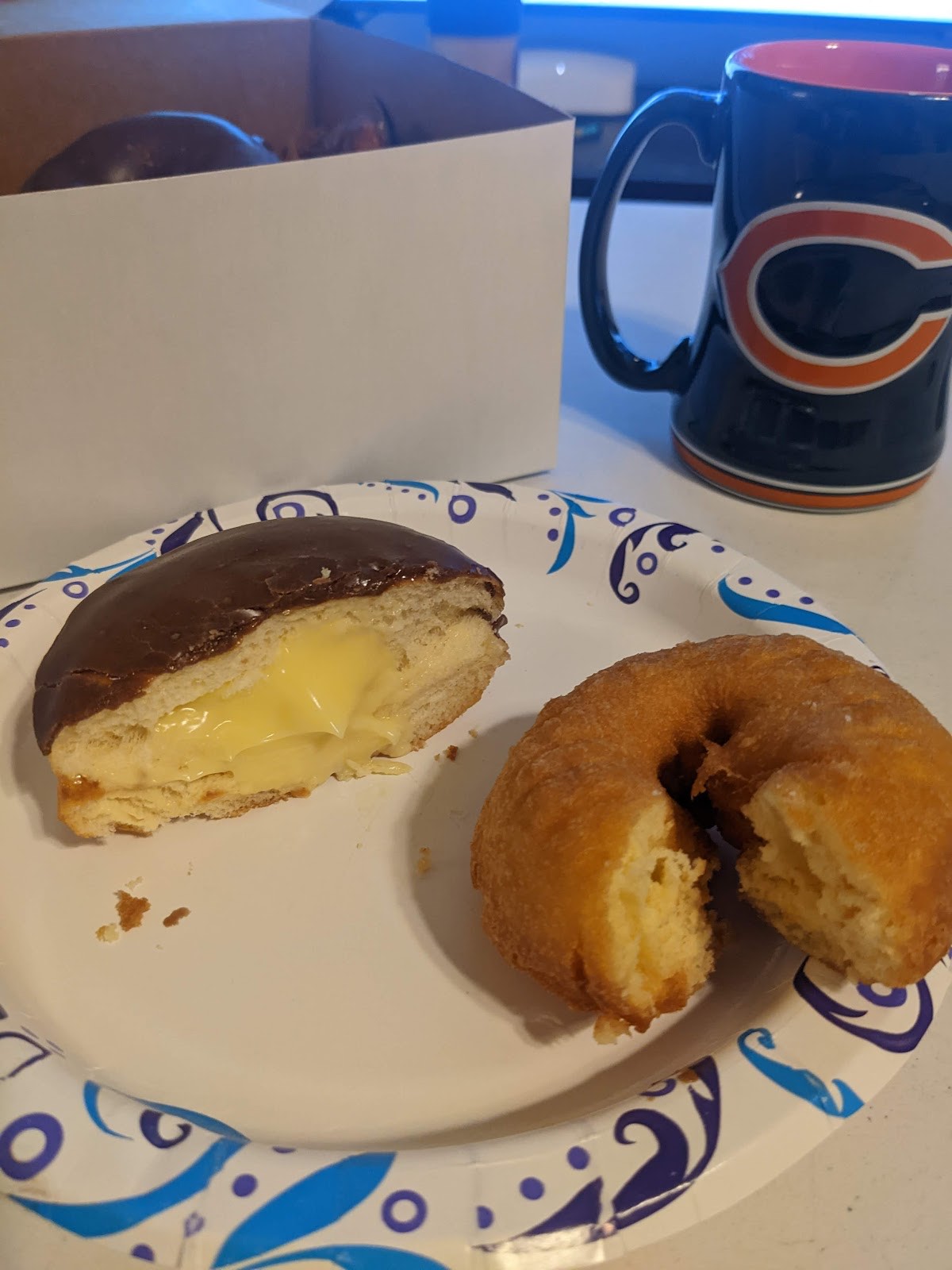 Boston crème donut cut open next to a plain cake donut and a coffee mug