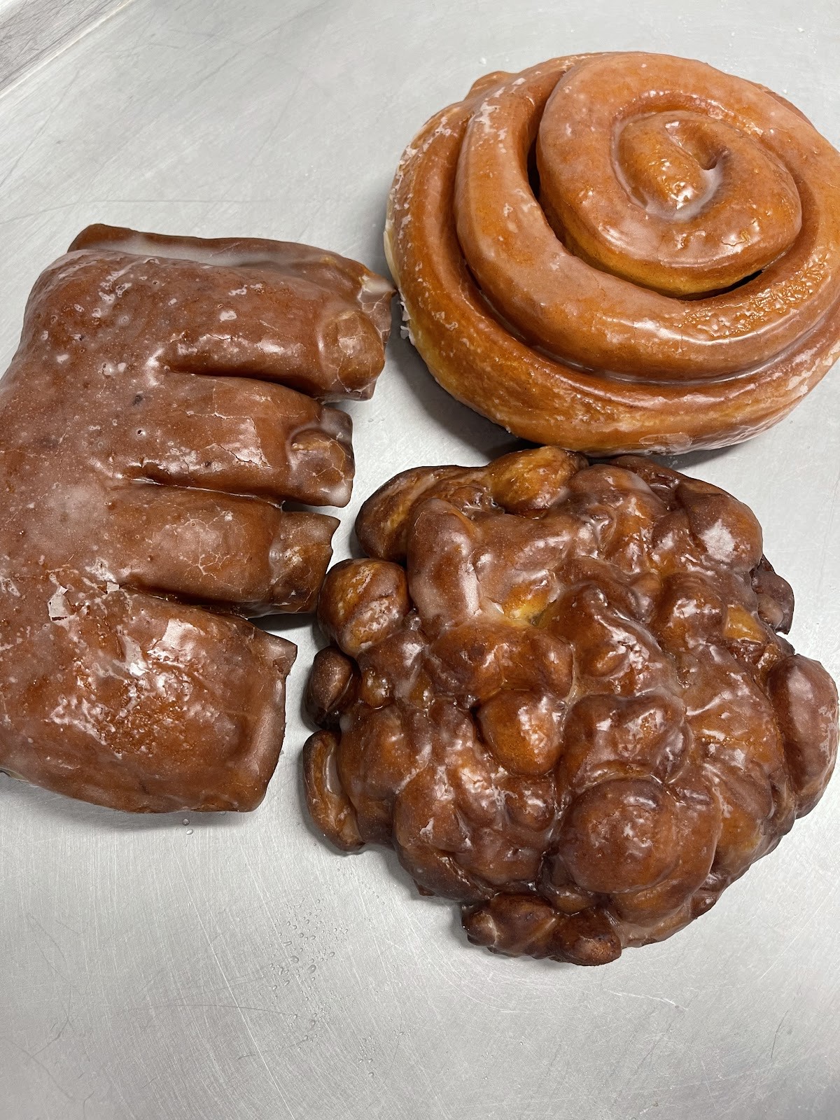 A glazed apple fritter and cinnamon roll from Gold Star Donuts, dripping with sweet glaze