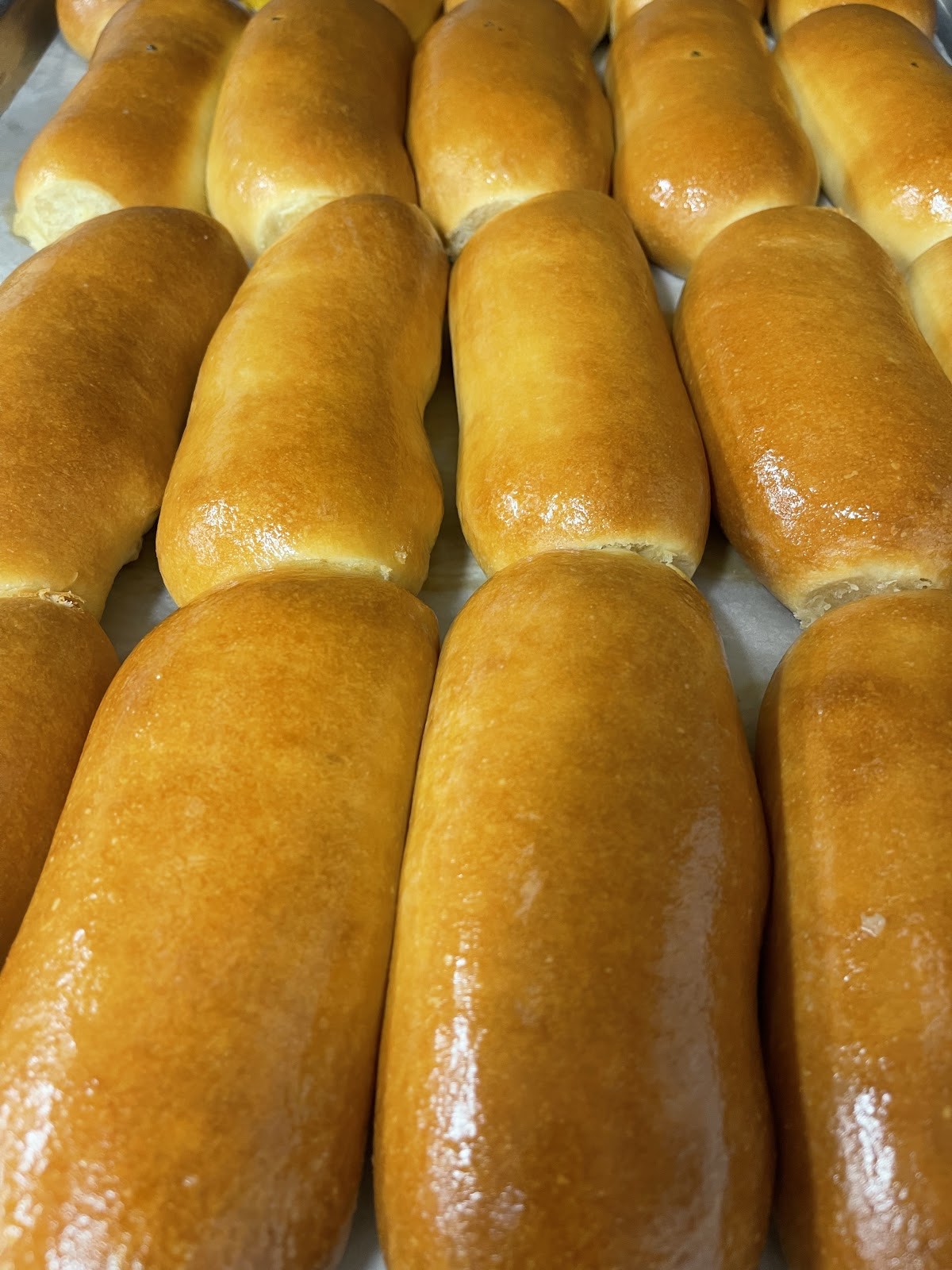 Rows of golden glazed long johns and butterflake finger rolls fresh from the fryer
